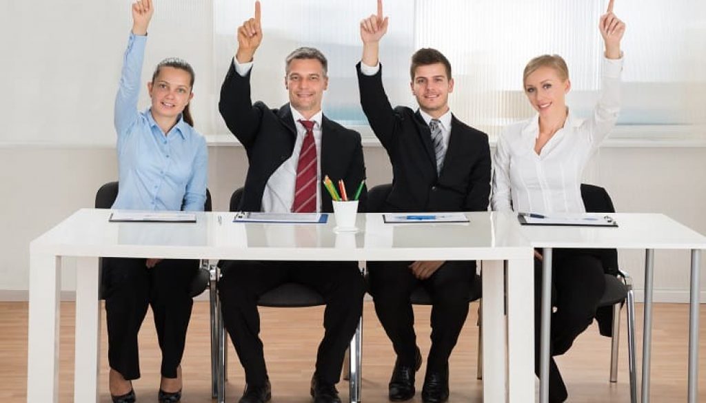 Businesspeople Raising Hands In Conference