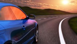 Blue car driving by autobahn in sunset with motion blur