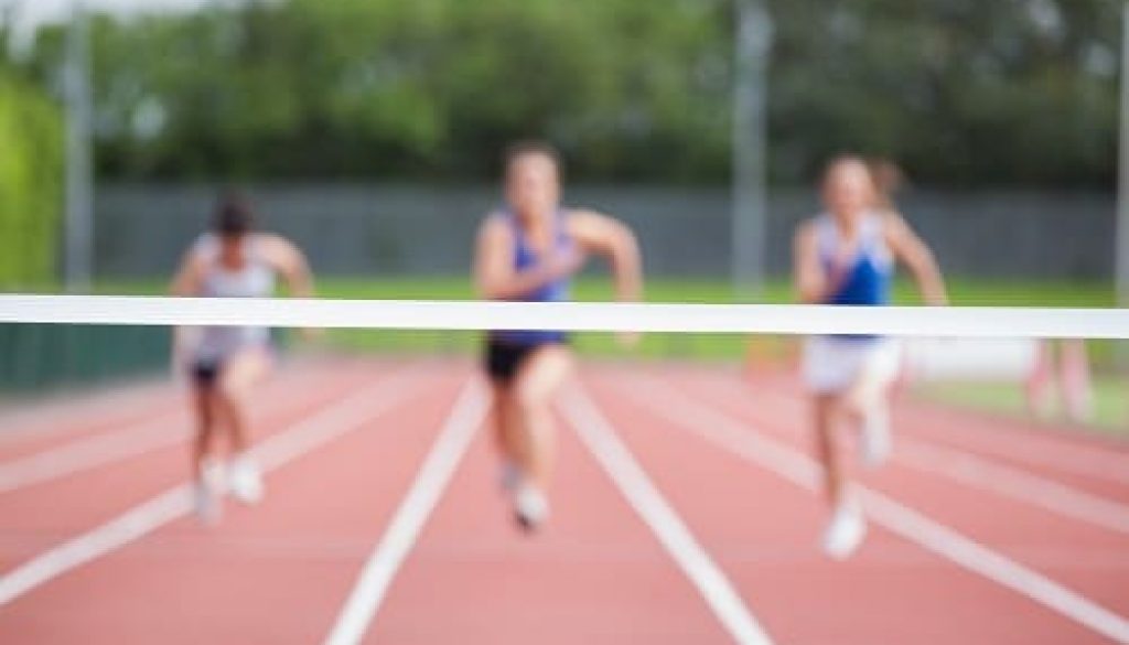 Female athletes running towards finish line on track field