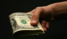 Image of a man holding money for an article about how to determine a good reverse auction procurement strategy.
