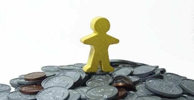 Image of a little yellow man atop a mountain of coins for an article about Why is Tail Spend Management Important but Often overlooked?.