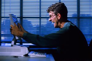 Image of a man grabbing and yelling at a computer for an article about why traditional sourcing methods are holding you back.